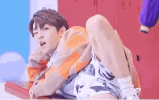a young man is laying on a table with his legs crossed and a woman is standing behind him .