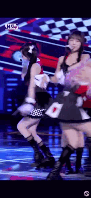 a group of girls are dancing on a stage while wearing costumes .