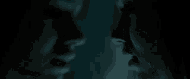 a man and a woman are touching their faces in the dark .