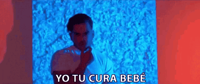 a man is standing in front of a blue wall with the words yo tu cura bebe written above him .