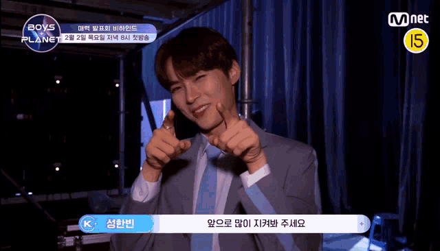 a man in a suit and tie giving a thumbs up in front of a mnet logo