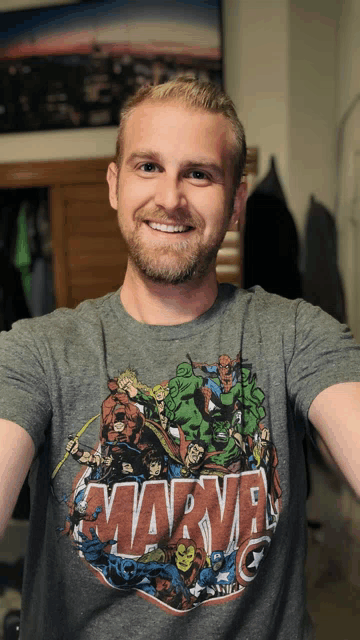 a man wearing a gray marvel t-shirt smiles for the camera