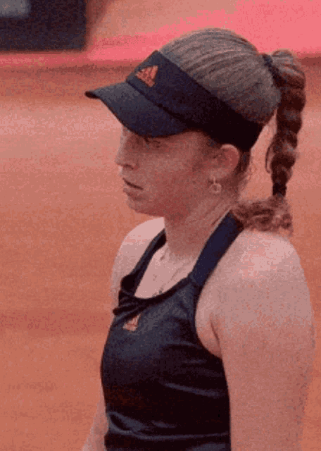 a woman wearing a black adidas hat and a blue tank top