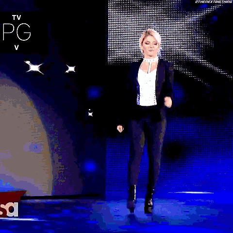 a woman in a suit is walking on a stage with the word raw on it