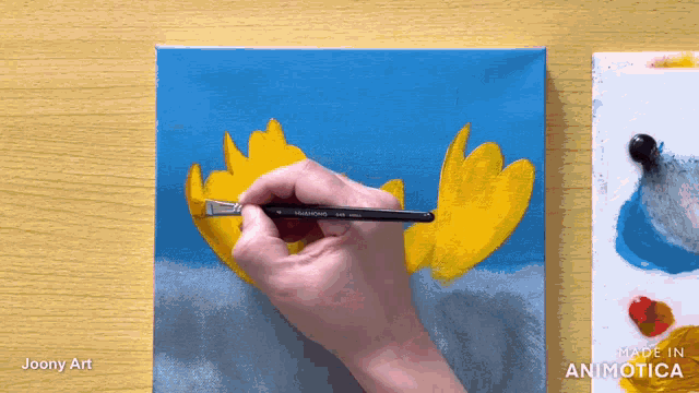 a person is painting a yellow flower on a blue background with the words made in animotica below them