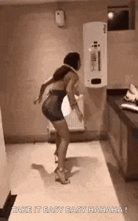 a woman is dancing in a bathroom with the words `` take it easy easy hahaha '' written on the bottom .