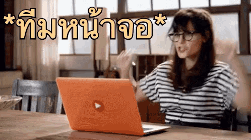 a woman sitting at a table with a laptop with a play button on it