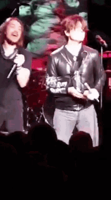 a man in a leather jacket is singing into a microphone