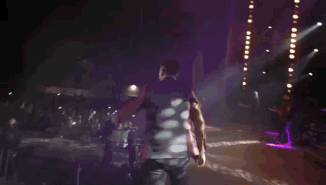 a man in a black vest is walking on a stage