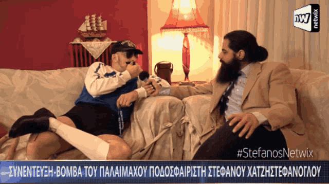 two men are sitting on a couch and one is holding a microphone with the words #stefanosnetwix on the bottom