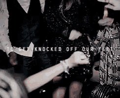 a group of people are dancing in a dark room with the words `` to get knocked off our feet '' on the bottom .