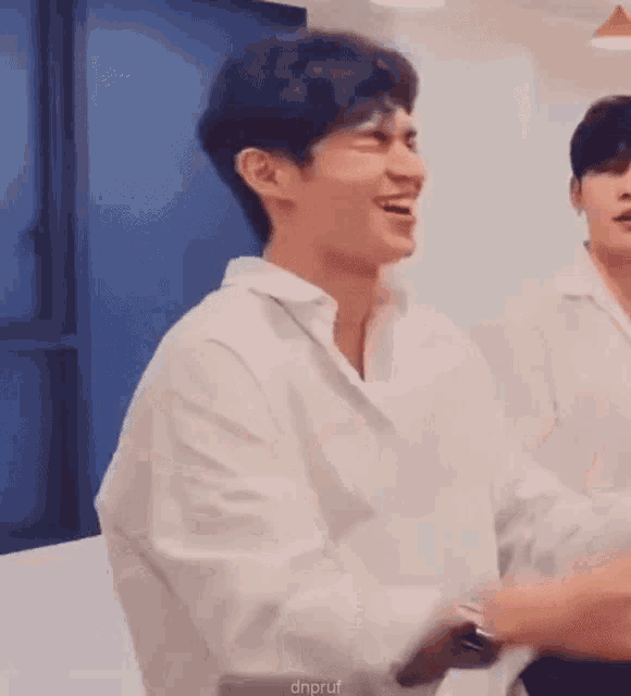 a man in a white shirt is laughing in a room .