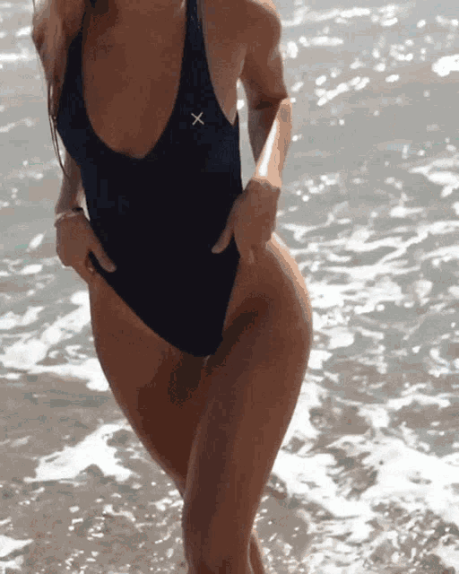 a woman in a black one piece swimsuit with an x on it