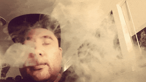 a man smoking a cigarette with smoke coming out of his nose