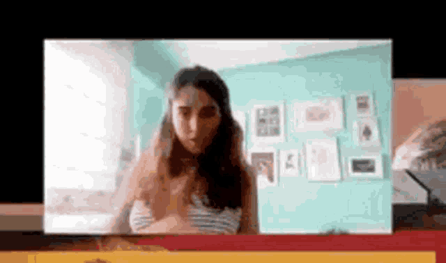a woman is standing in front of a blue wall in a video call .