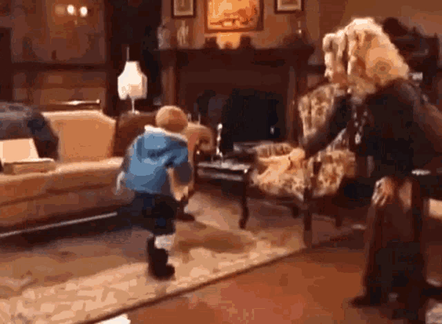 a little boy in a blue jacket is running in a living room