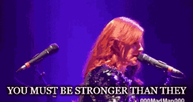 a woman singing into a microphone with the words " you must be stronger than they " above her