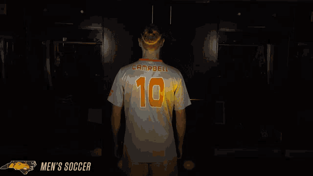 a man in a number 10 jersey stands in a dark locker room