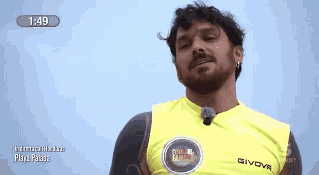 a man wearing a yellow givova shirt is standing in front of a blue sky