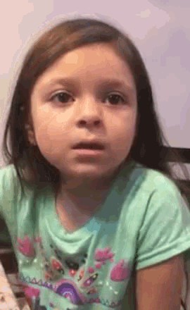 a little girl is wearing a green shirt with a unicorn on it