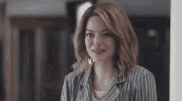 a woman in a striped jacket is smiling while standing in a room .