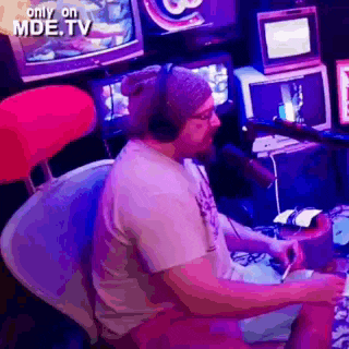 a man wearing headphones and a hat is playing a video game .