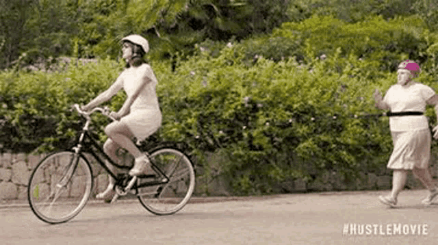 a woman is riding a bicycle next to an older woman .