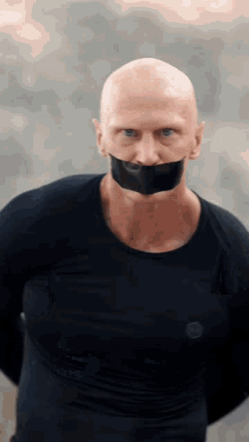 a bald man with a black tape around his mouth