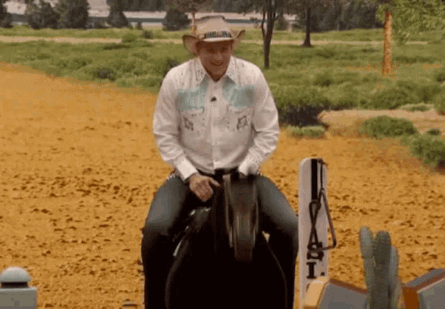 a man in a cowboy hat is riding a horse in a field