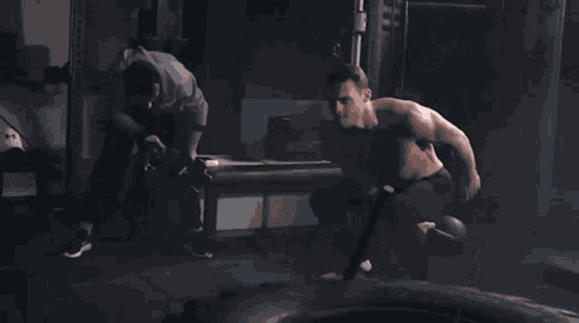 a man without a shirt is throwing a kettlebell in a gym