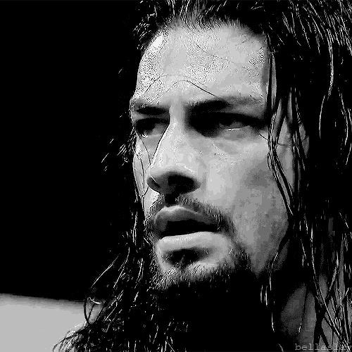 a black and white photo of a man with long hair and a beard looking at the camera .