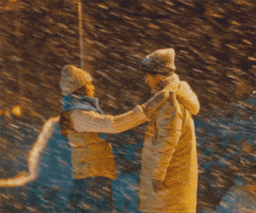 a man and a woman are holding hands in the snow at night