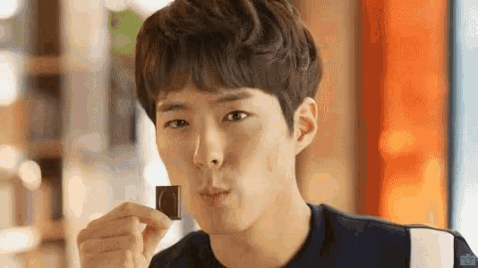 a young man is eating a piece of chocolate with his mouth open .