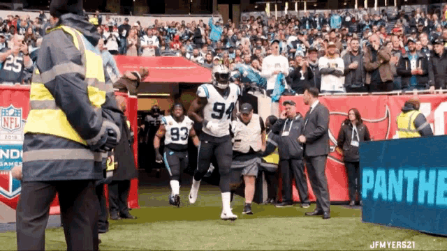 a panthers football player wearing number 94 walks on the field