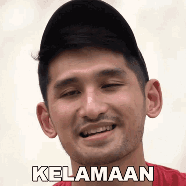 a man with a beard wearing a black hat and a red shirt with the word kelaman on his face
