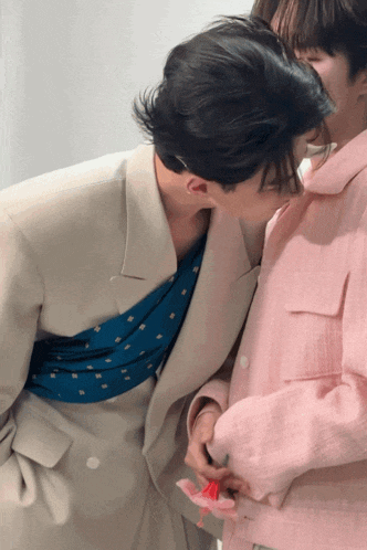 a man in a pink jacket kisses a woman on the cheek
