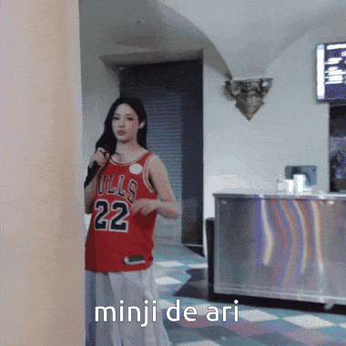 a woman wearing a red bulls jersey stands in a room