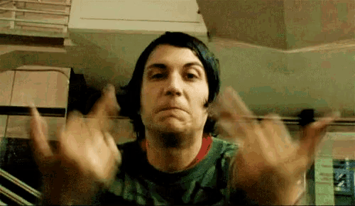 a man in a green shirt is making a face and giving the middle finger .