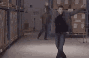 a man is dancing in a warehouse while a woman watches .