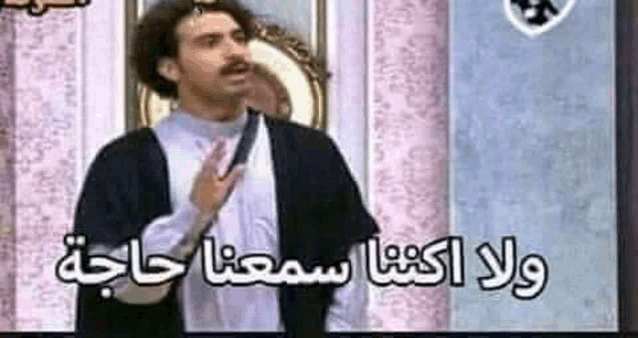 a man with a mustache is standing in front of a mirror and talking in arabic .