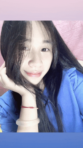 a woman wearing a blue shirt has her hand on her hair