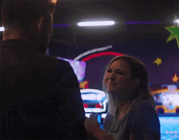a man and a woman are looking at each other in a dark room .
