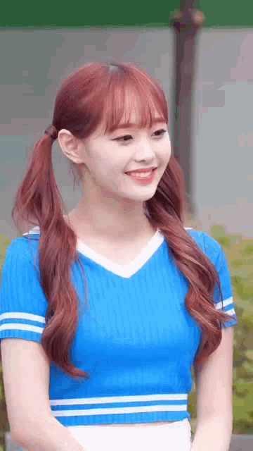 a girl with red hair and pigtails is wearing a blue shirt .