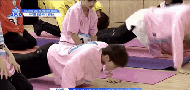 a man in a pink shirt is doing push ups on another man 's back ..