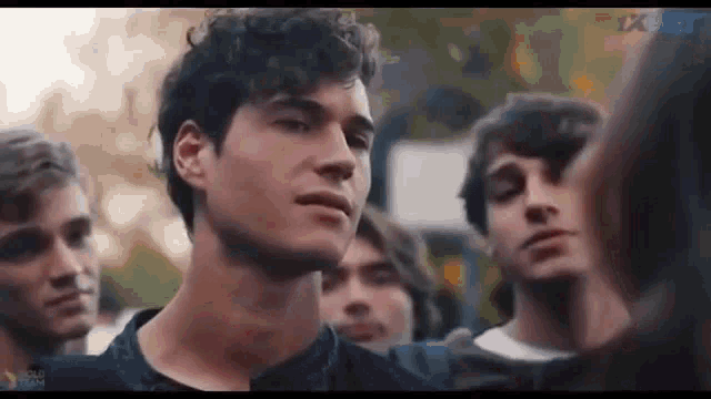 a man with curly hair is standing in a crowd of people and looking at the camera .