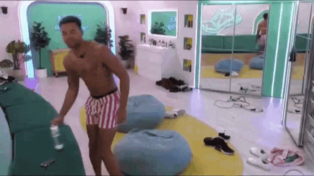a shirtless man in striped shorts is standing in a room