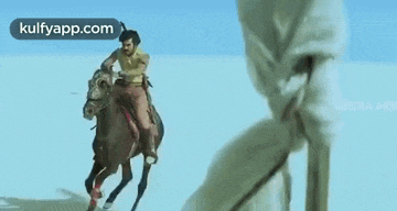 a man is riding on the back of a horse in the snow .