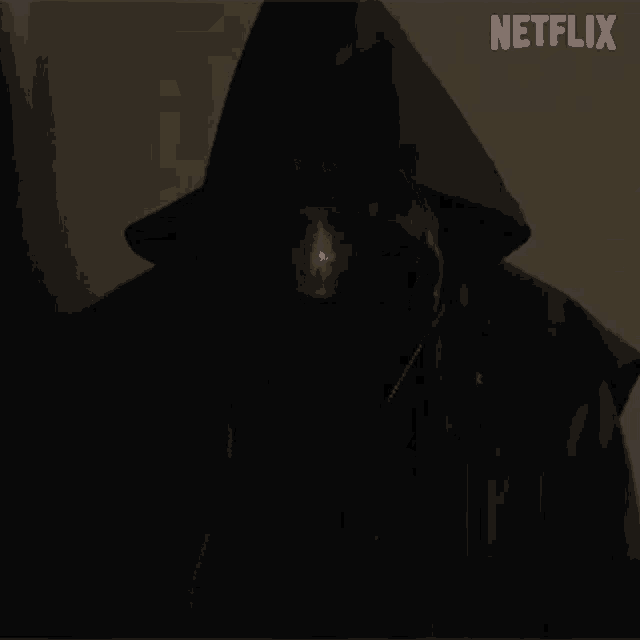 a man in a hooded jacket is standing in a dark room with a netflix logo in the background .