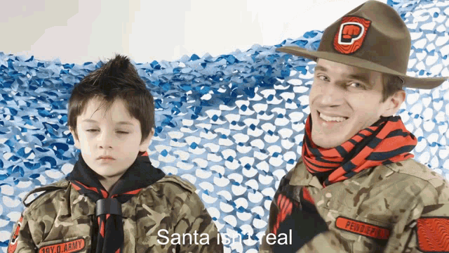 a boy in a boy scout uniform stands next to a man in a military uniform with the words santa is real on the screen