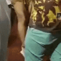 a man in a camouflage shirt and blue shorts is standing next to a woman in a bathroom .